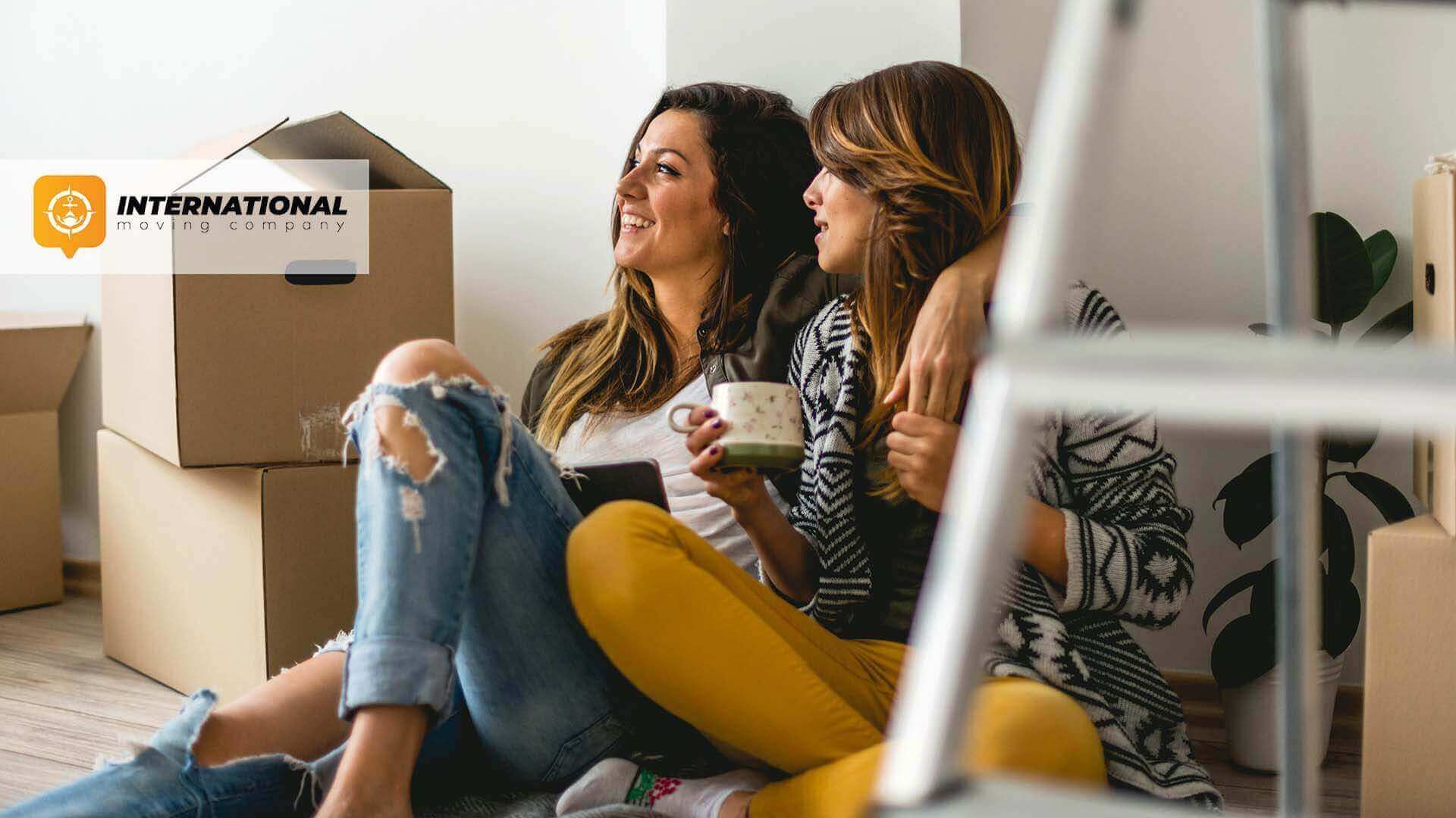 Two women sitting on the floor after moving internationally